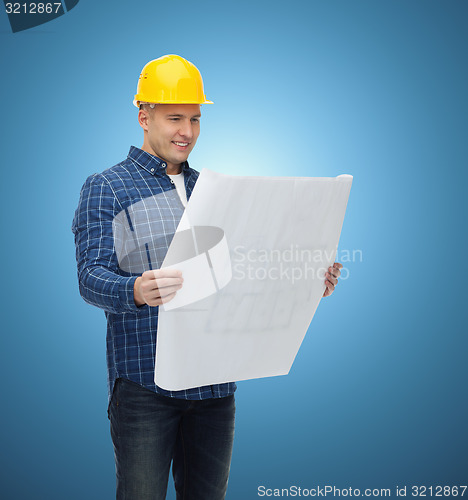 Image of smiling male builder in helmet with blueprint