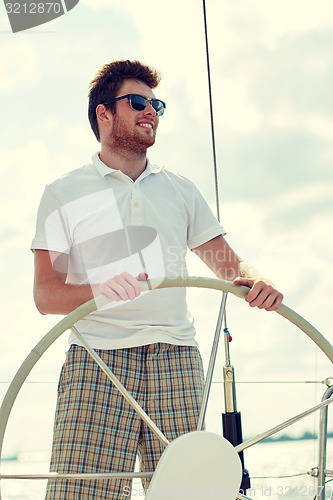 Image of young man in sunglasses steering wheel on yacht