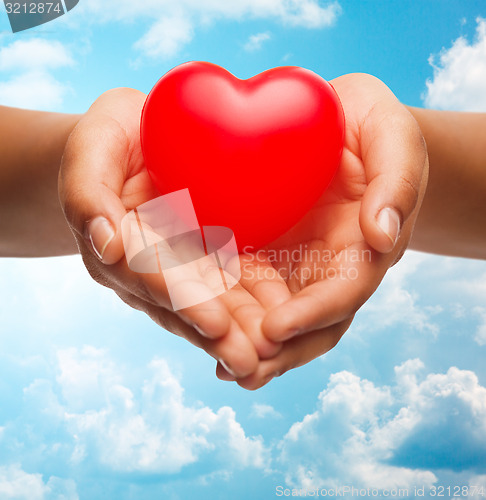 Image of close up of female hands holding small red heart