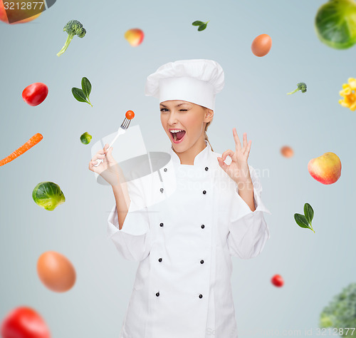 Image of smiling female chef with fork and tomato