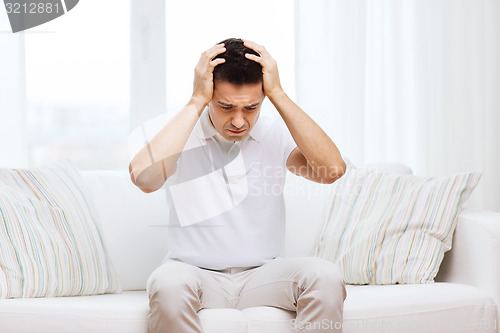 Image of unhappy man suffering from head ache at home