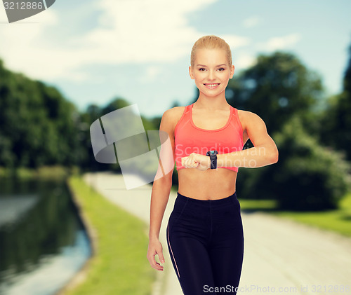 Image of smiling woman with heart rate monitor on hand