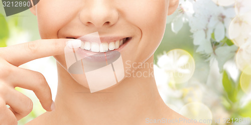 Image of close up of smiling woman face pointing to teeth