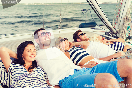 Image of smiling friends lying on yacht deck
