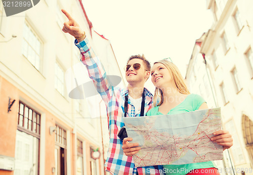Image of smiling couple with map and photo camera in city