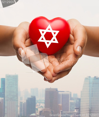 Image of close up of hands holding heart with jewish star