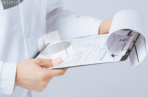 Image of male doctor holding prescription paper in hand