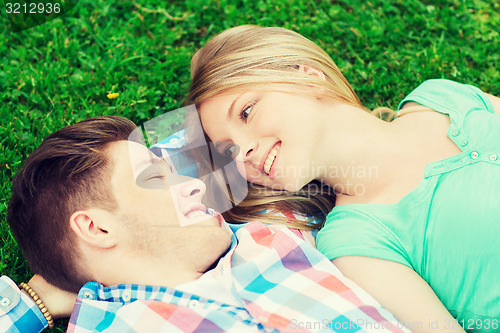 Image of smiling couple lying on grass in park