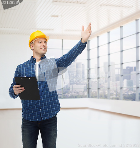 Image of smiling male builder in helmet with clipboard