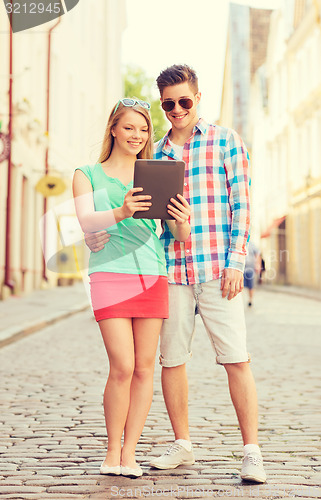 Image of smiling couple with tablet pc in city