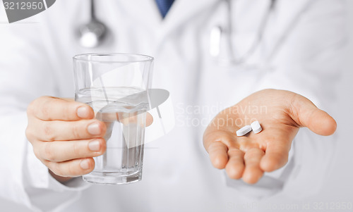 Image of doctor hands giving white pills and glass of water