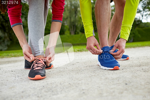 Image of close up of couple tying shoelaces outdoors