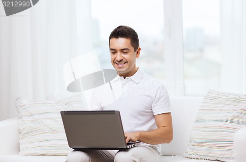 Image of happy man working with laptop computer at home