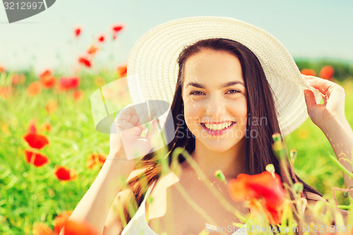 Image of smiling young woman in straw hat on poppy field