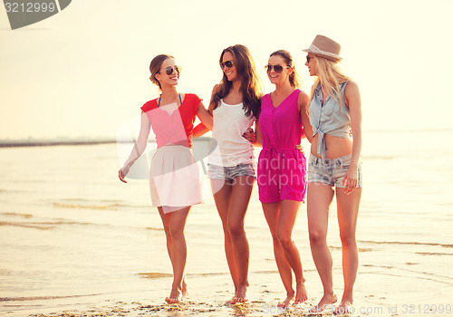 Image of group of smiling women in sunglasses on beach