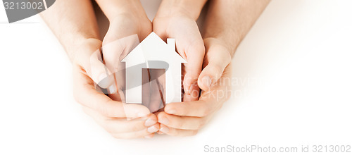 Image of man and woman hands with white paper house