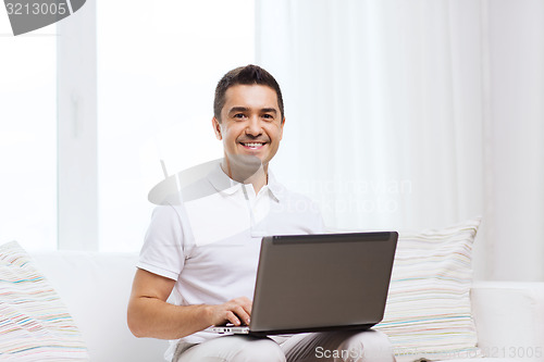Image of happy man working with laptop computer at home