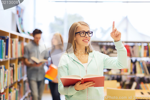 Image of happy student girl or woman with book in library