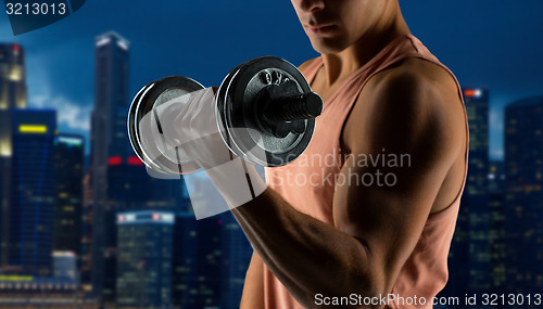 Image of close up of young man with dumbbell flexing biceps