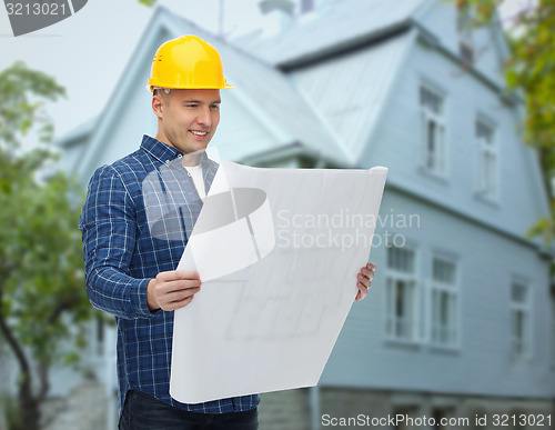 Image of smiling builder with blueprint over house