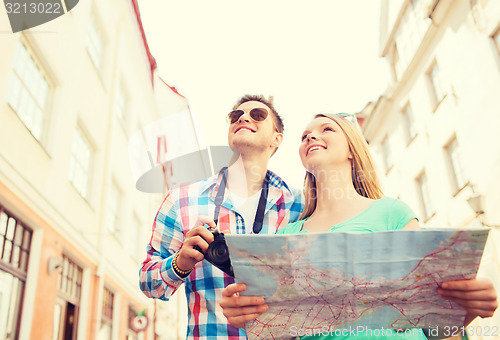 Image of smiling couple with map and photo camera in city