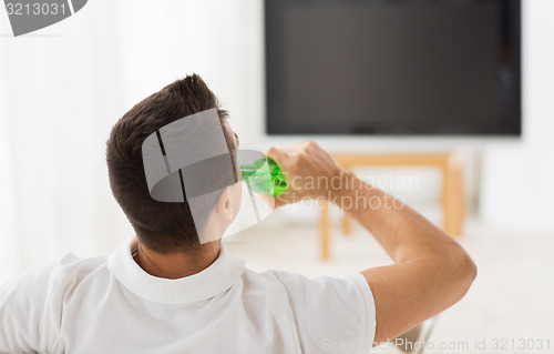 Image of man watching tv and drinking beer at home