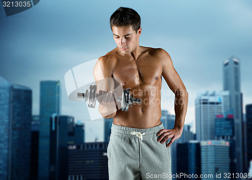 Image of young man with dumbbell flexing biceps