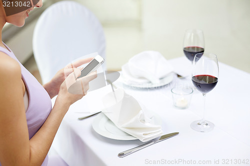 Image of close up of woman with smartphone at restaurant
