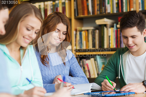 Image of happy students writing to notebooks in library