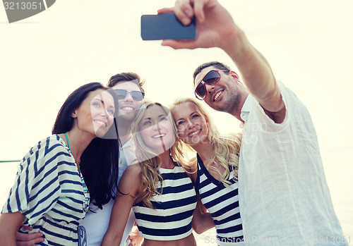 Image of happy friends on beach and taking selfie