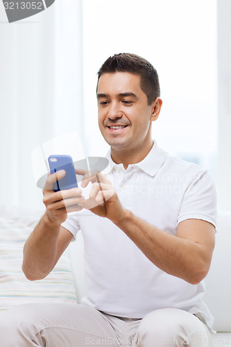 Image of happy man with smartphone at home
