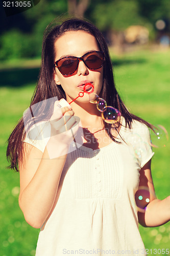 Image of smiling young girl with soap bubbles in park