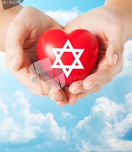 Image of close up of hands holding heart with jewish star