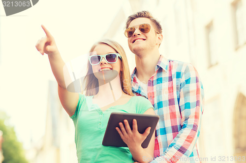Image of smiling couple with tablet pc in city