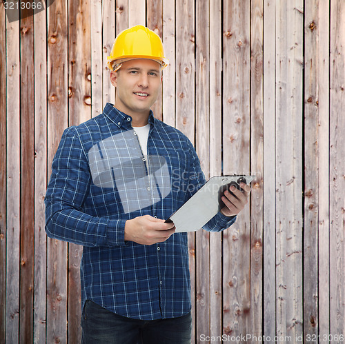 Image of smiling male builder in helmet with clipboard