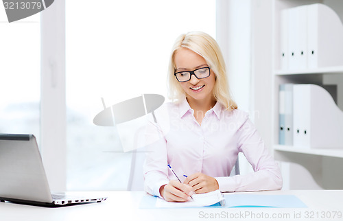 Image of smiling businesswoman reading papers in office