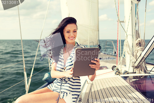 Image of smiling woman sitting on yacht with tablet pc