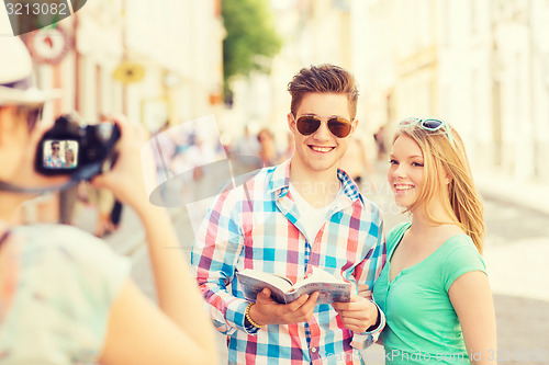 Image of smiling couple with map and photo camera in city