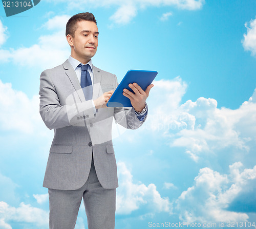 Image of happy businessman in suit holding tablet pc