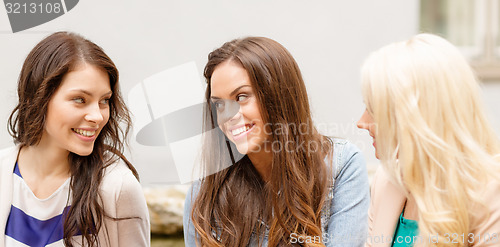 Image of three beautiful girls drinking coffee in cafe