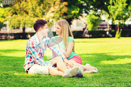 Image of smiling couple sitting on grass in park