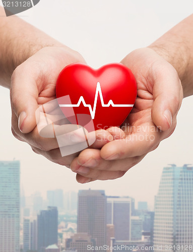 Image of close up of hands holding heart with cardiogram