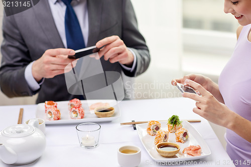 Image of close up of couple with smartphones at restaurant