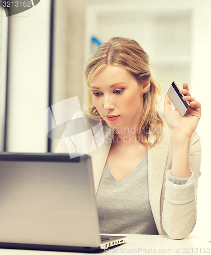 Image of serious woman with laptop computer and credit card