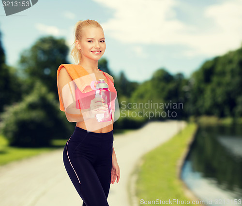 Image of smiling sporty woman with water bottle and towel