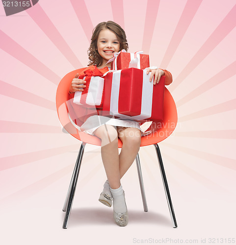 Image of happy little girl with gift boxes sitting on chair