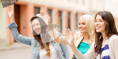 Image of three beautiful girls waving hands