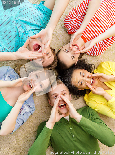 Image of smiling people lying down on floor and screaming