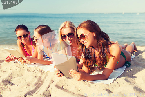 Image of group of smiling young women with tablets on beach