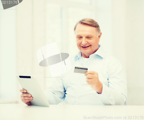 Image of old man with tablet pc and credit card at home